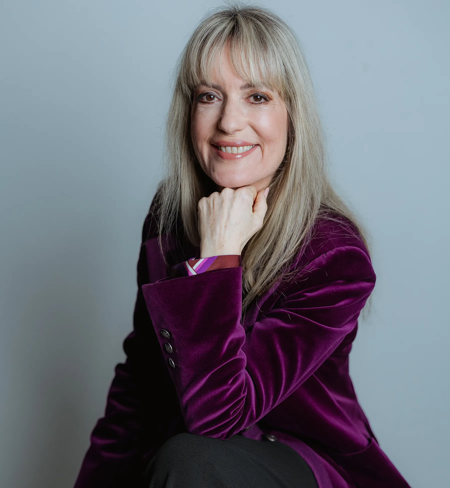 Astrid Dahl Beziehungsexpertin Portrait mit lila Samtjacke und Hand am Kinn
