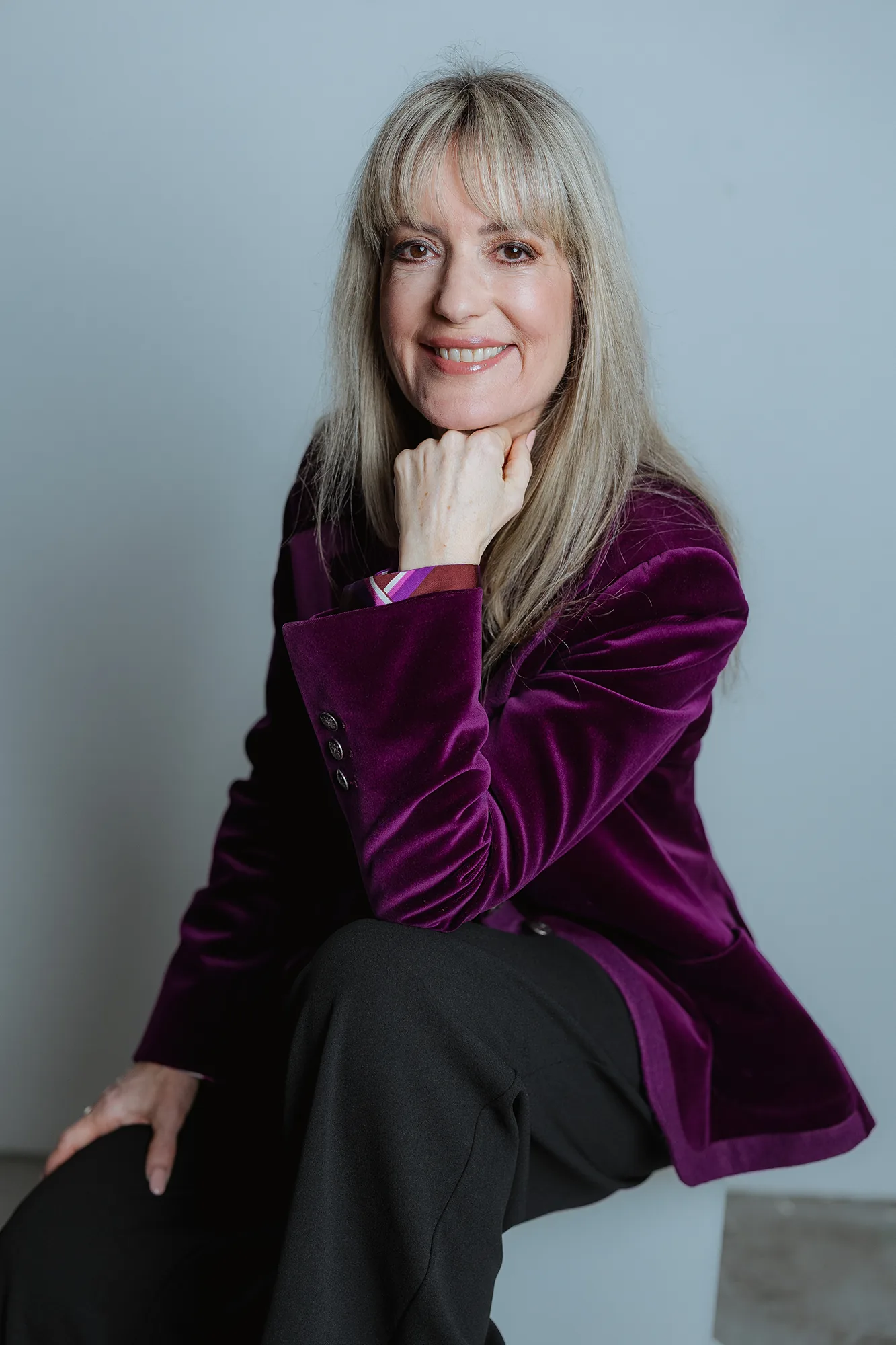 Astrid Dahl Beziehungsexpertin Portrait mit lila Samtjacke und Hand am Kinn